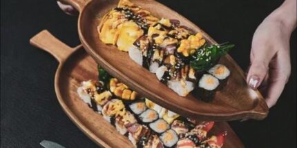 Leaf wooden platter on a black table with food on it.