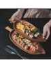 Leaf wooden platter on a black table with food on it.